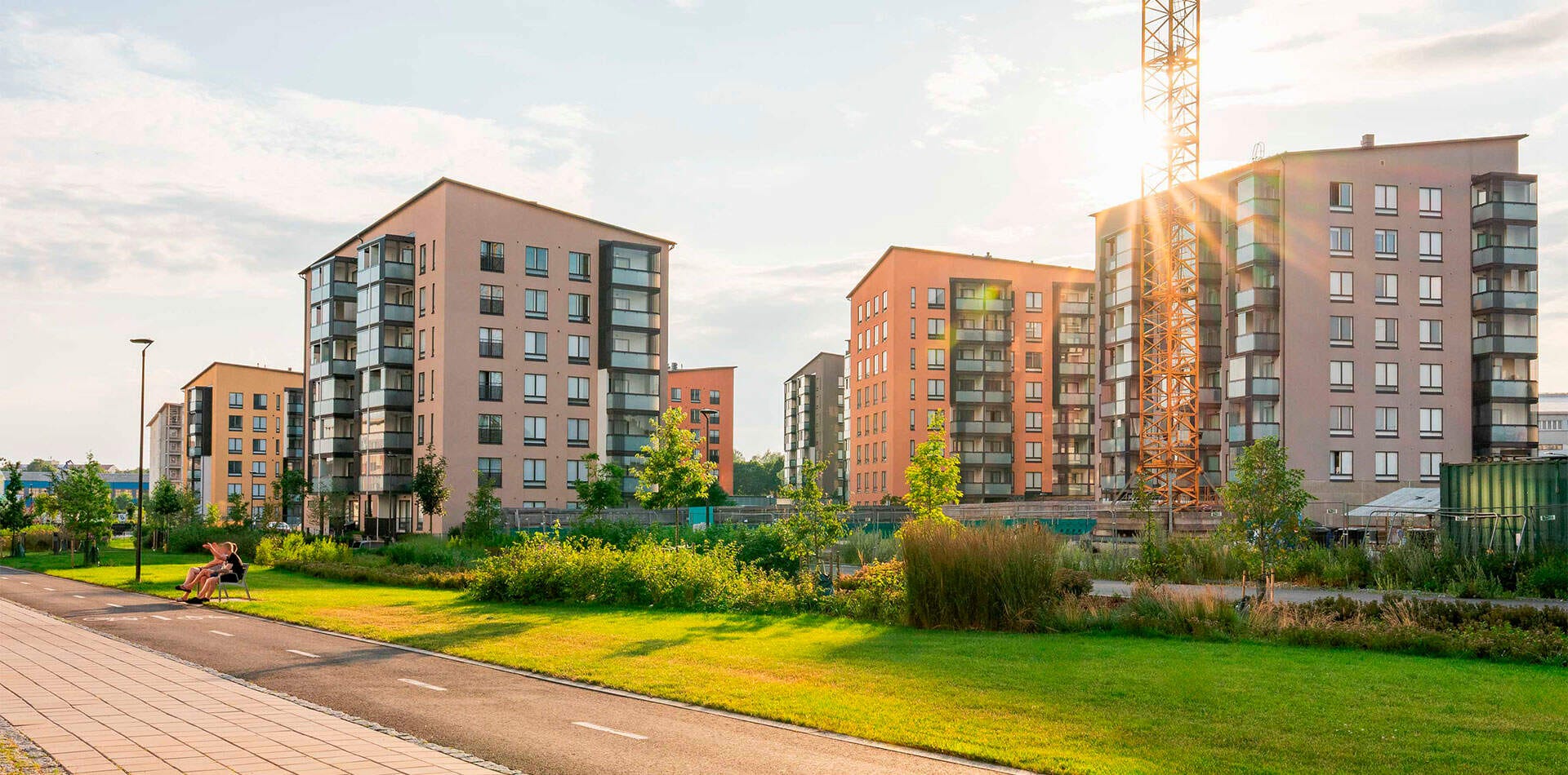 Valokuva - Moderni Kirstinpuiston kerrostaloalue, jossa on useita vaaleita rakennuksia. Rauhallinen ympäristö, vehreät puistot ja hyvät ulkoilumahdollisuudet.