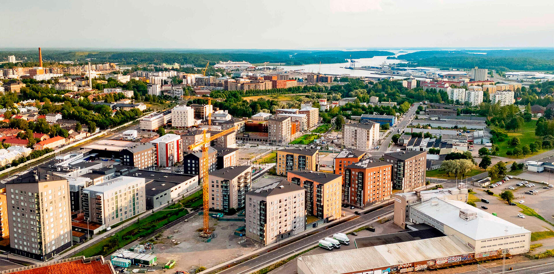 Valokuva - Ilmakuva, joka esittelee Kirstinpuiston kaupunkinäkymän, jossa on useita moderneja kerrostaloja ja satama taustalla.