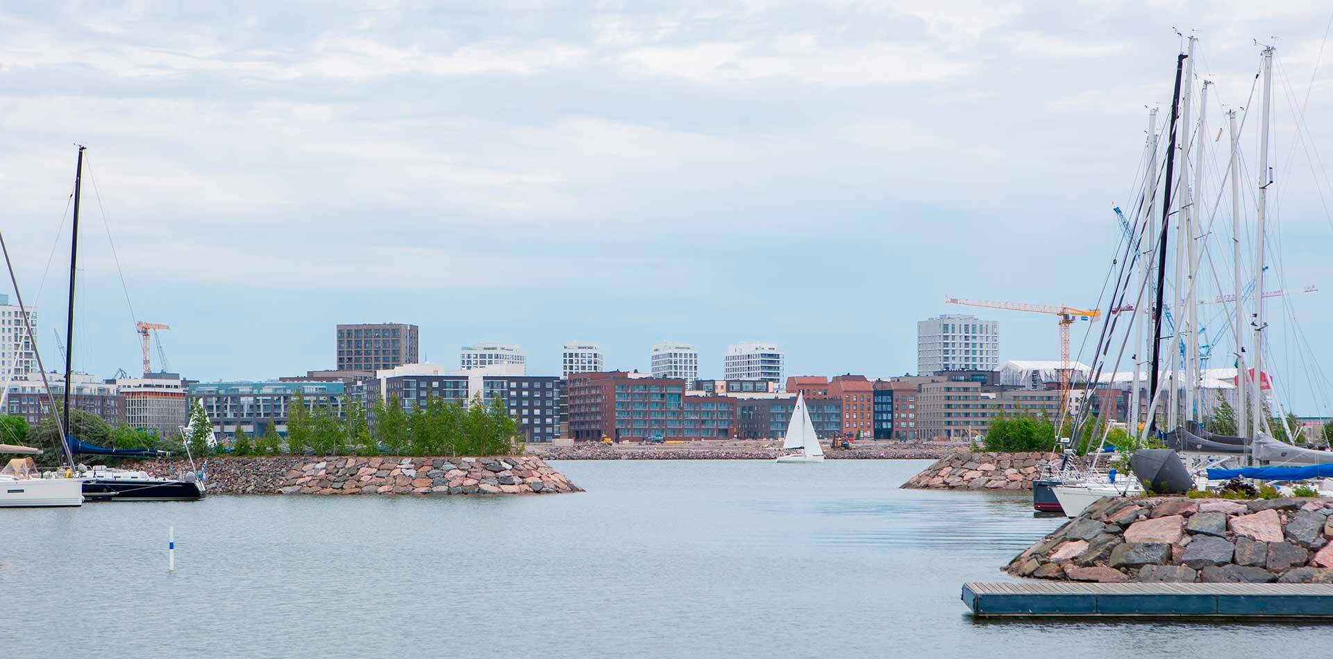 Valokuva - Taustalla Jätkäsaaren kaupunginosa ja modernit kerrostalot meren rannalla.